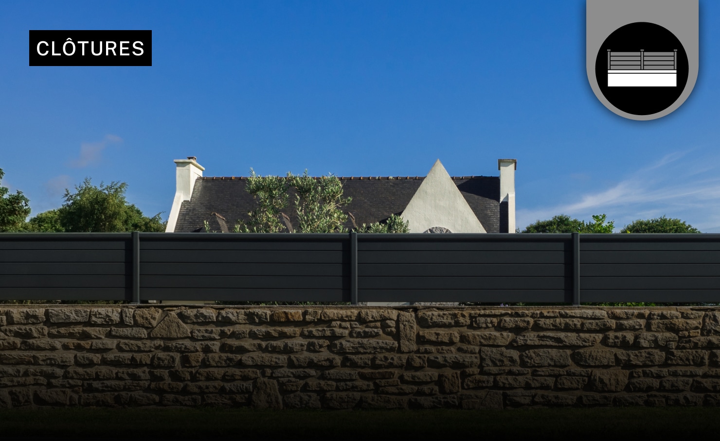 Clôture métallique grise fixer sur un mur en pierre avec une maison individuelle en fond